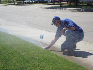 a Hamilton sprinkler repair pro is adjusting a pop-up head